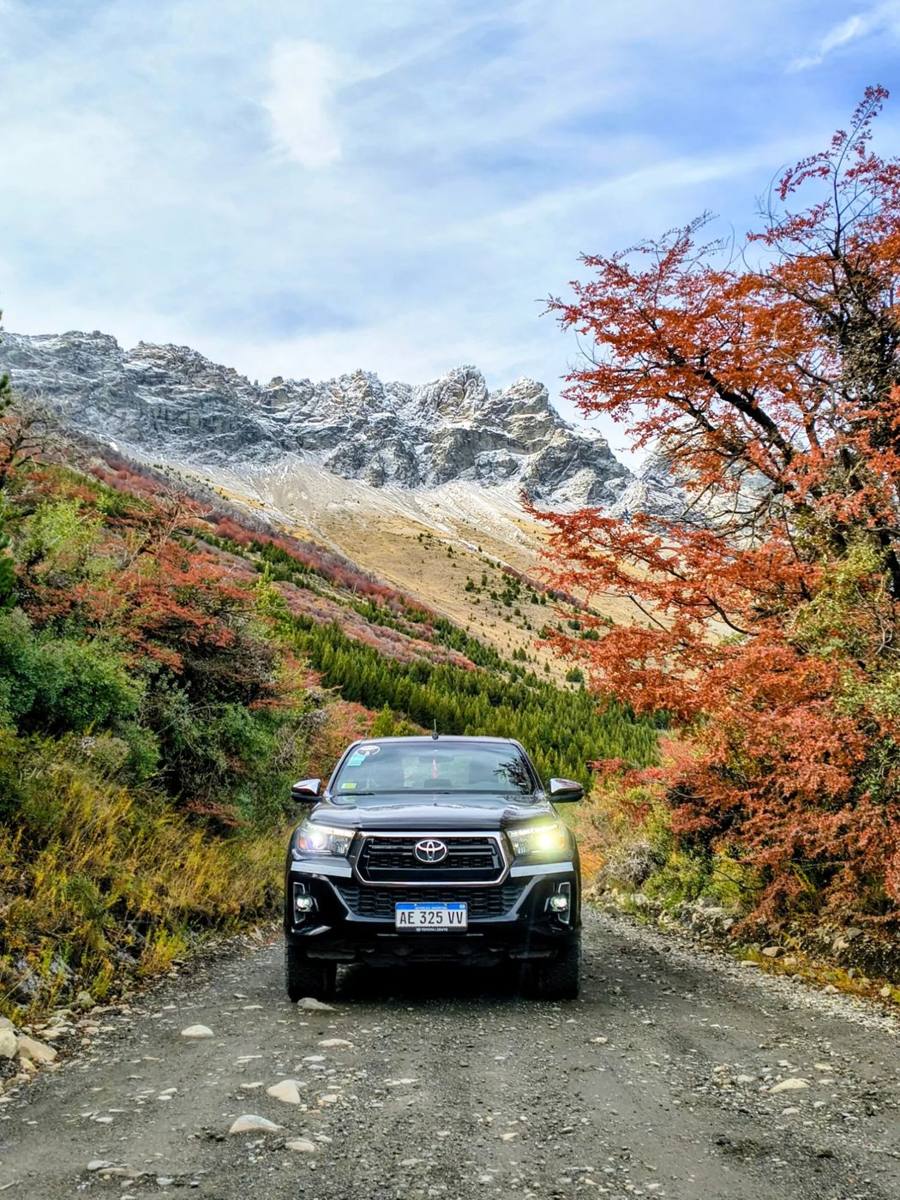 Camioneta en un camino de montaña entre árboles de otoño